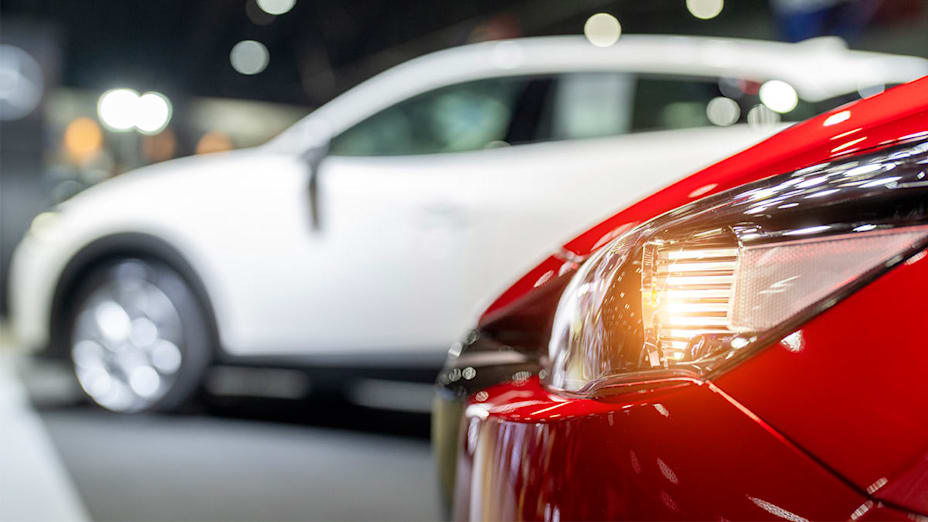 Close up of a car's headlight with another car out of focus in the background.