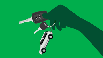 Hand-holding car keychain and keys on a green background.